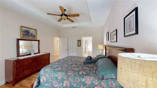 bedroom featuring connected bathroom, a raised ceiling, and ceiling fan