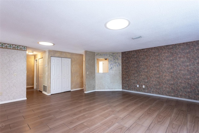 empty room with hardwood / wood-style floors and a textured ceiling