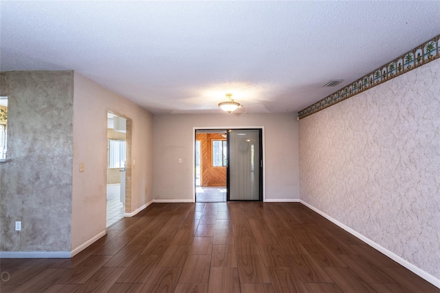 spare room with a textured ceiling and dark hardwood / wood-style flooring