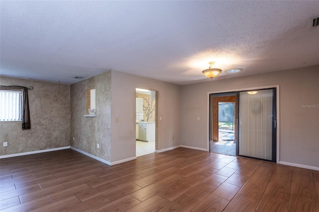 spare room with a textured ceiling and wood-type flooring