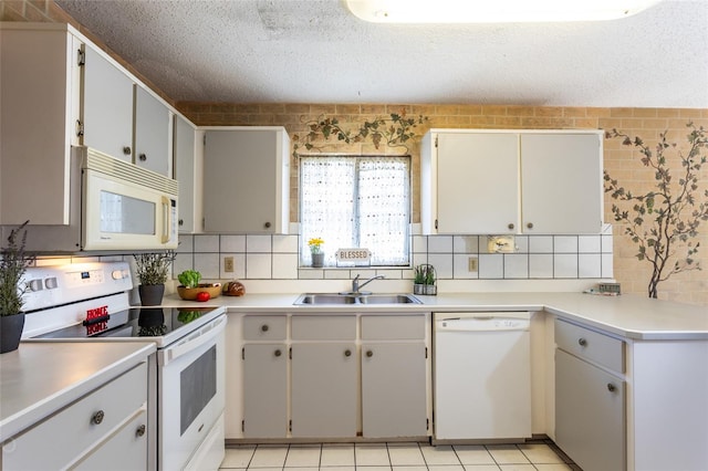 kitchen featuring white appliances, sink, a textured ceiling, white cabinetry, and light tile patterned floors