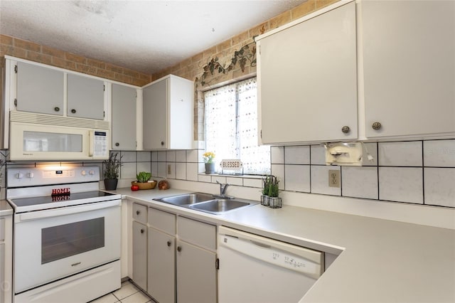 kitchen with sink, light tile patterned floors, backsplash, and white appliances