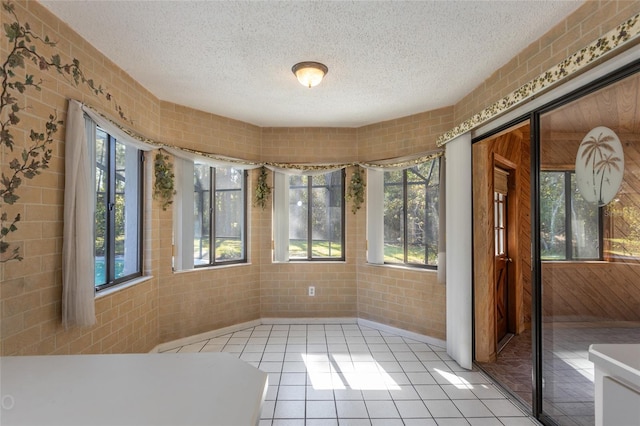 interior space featuring a textured ceiling, a healthy amount of sunlight, and light tile patterned floors