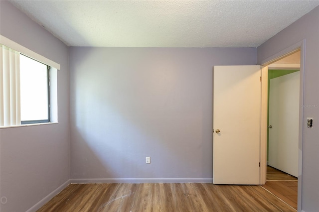 unfurnished room featuring a textured ceiling and light hardwood / wood-style flooring