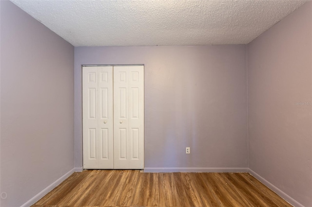 unfurnished bedroom with a closet, hardwood / wood-style flooring, and a textured ceiling