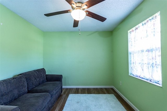 living room featuring a wealth of natural light, a textured ceiling, dark hardwood / wood-style floors, and ceiling fan