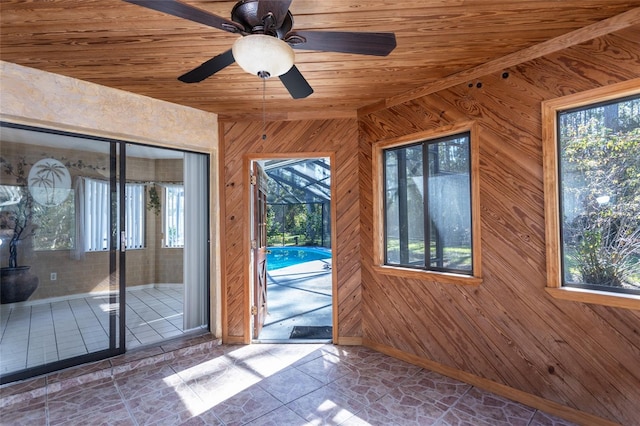 doorway featuring wooden walls, wood ceiling, and ceiling fan