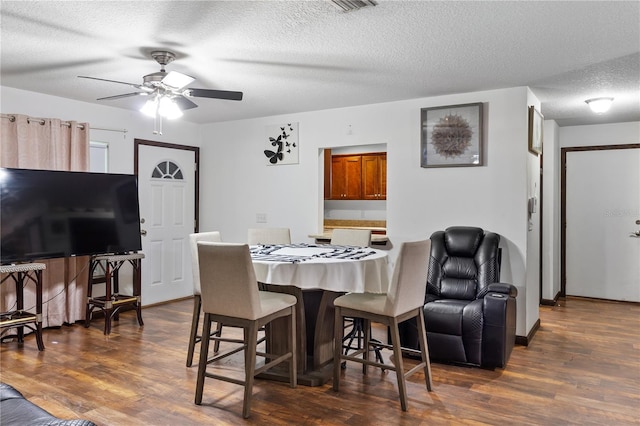 dining area with ceiling fan, a textured ceiling, and dark hardwood / wood-style flooring