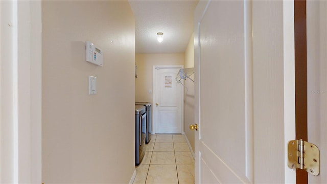 laundry area with independent washer and dryer, a textured ceiling, and light tile patterned floors