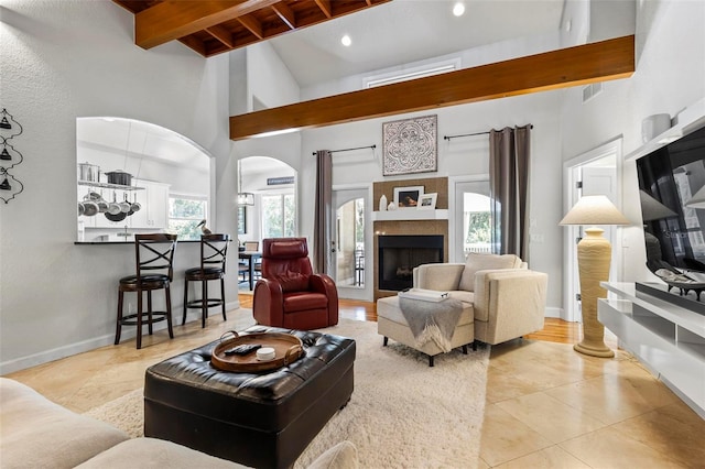 living room featuring beamed ceiling, high vaulted ceiling, and light tile patterned floors