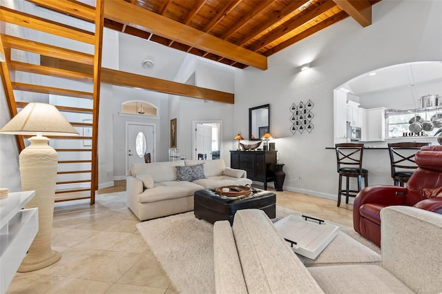 tiled living room featuring beam ceiling, wooden ceiling, and a high ceiling