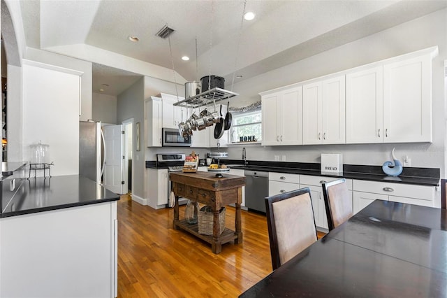 kitchen with hardwood / wood-style flooring, stainless steel appliances, a textured ceiling, and white cabinets