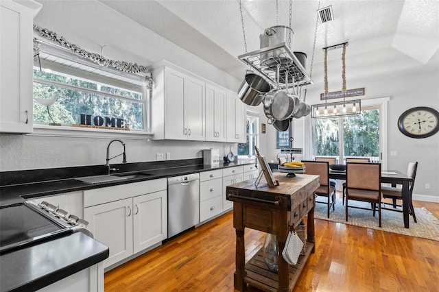 kitchen with white cabinetry, dishwasher, a textured ceiling, and decorative light fixtures