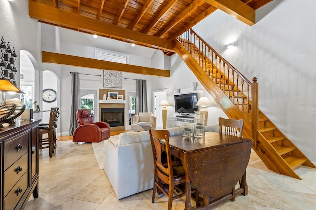 living room featuring a towering ceiling, beam ceiling, wooden ceiling, and light tile patterned floors