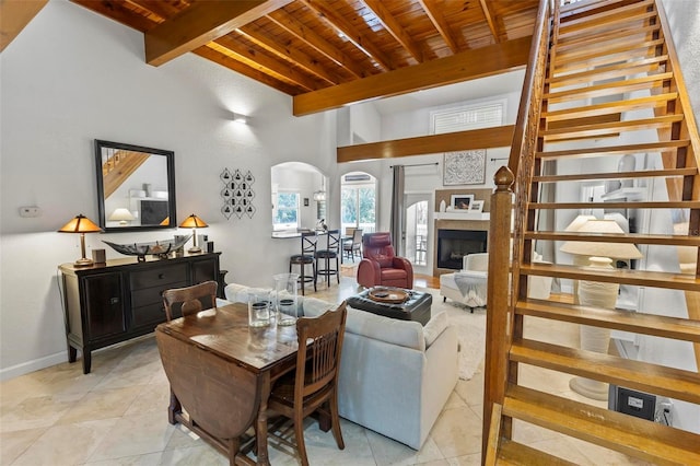 living room featuring wood ceiling, beam ceiling, a high ceiling, and light tile patterned floors