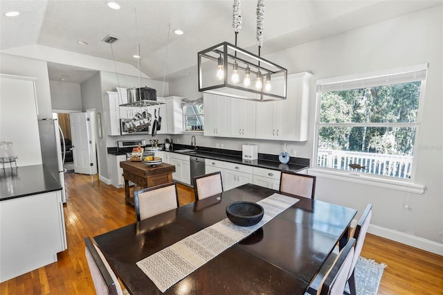 dining space featuring hardwood / wood-style flooring, sink, and vaulted ceiling