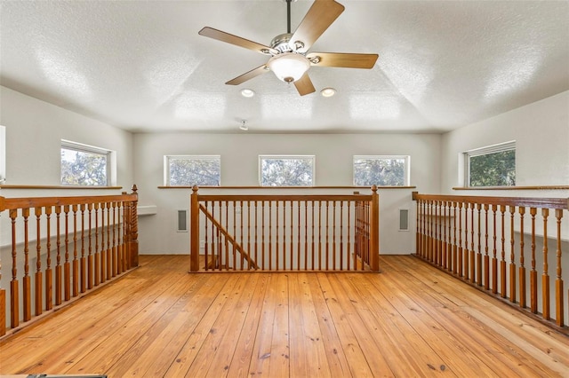 additional living space featuring a textured ceiling, light hardwood / wood-style floors, and ceiling fan