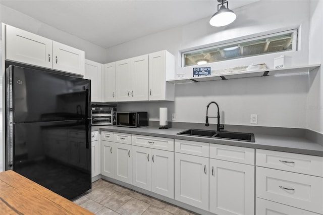 kitchen featuring white cabinetry, light tile patterned floors, black appliances, and sink