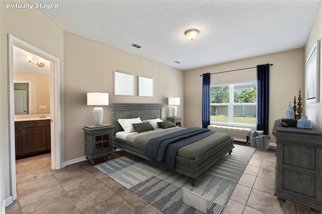 tiled bedroom featuring ensuite bath and a textured ceiling