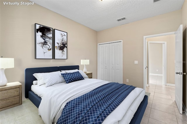 bedroom featuring light tile patterned floors, a closet, visible vents, a textured ceiling, and baseboards