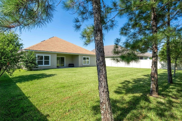 back of property featuring a lawn, fence, and stucco siding