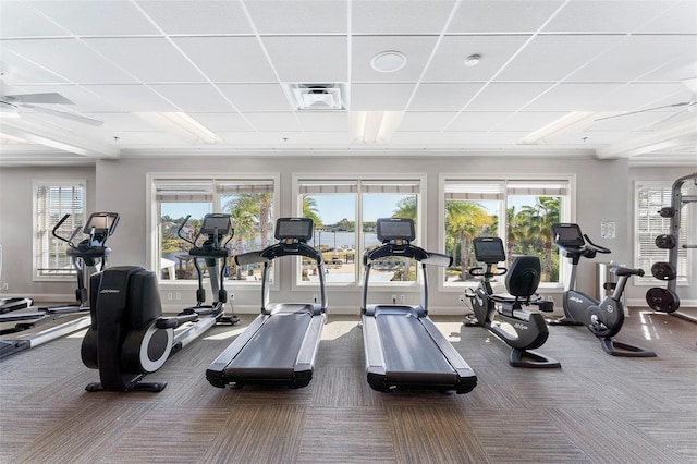 gym featuring visible vents, dark carpet, a drop ceiling, and baseboards