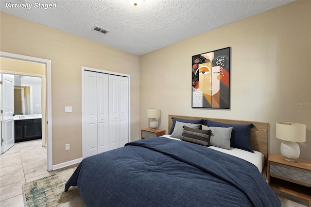 bedroom featuring baseboards, visible vents, a textured ceiling, a closet, and light tile patterned flooring