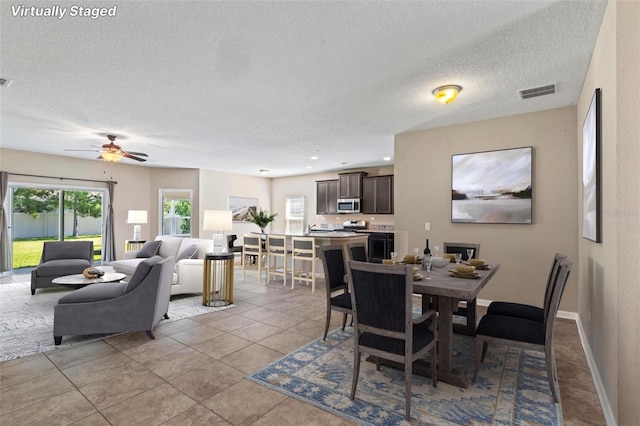 dining space with a textured ceiling, light tile patterned floors, visible vents, and a wealth of natural light