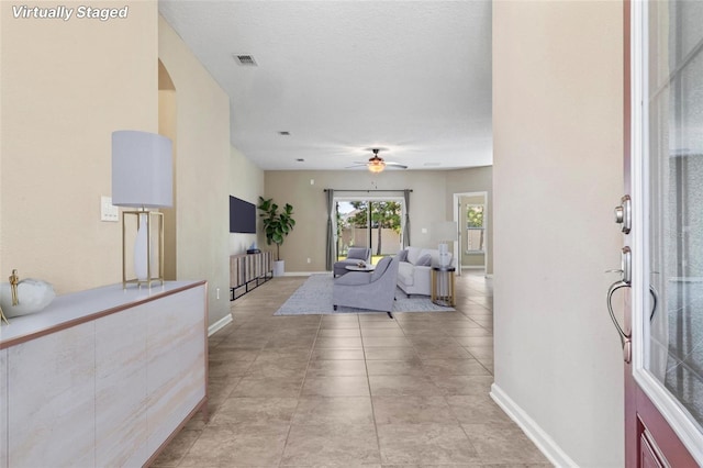 foyer entrance with baseboards, visible vents, ceiling fan, a textured ceiling, and light tile patterned flooring