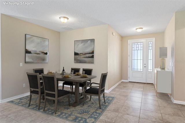 dining room with a textured ceiling, light tile patterned flooring, and baseboards