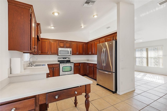 kitchen with appliances with stainless steel finishes, light tile patterned flooring, sink, and vaulted ceiling