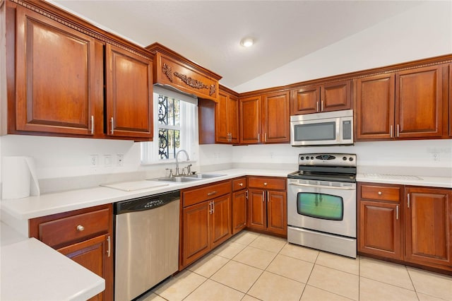 kitchen featuring sink, vaulted ceiling, stainless steel appliances, and light tile patterned floors