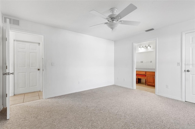 unfurnished bedroom featuring ensuite bath, light colored carpet, and ceiling fan