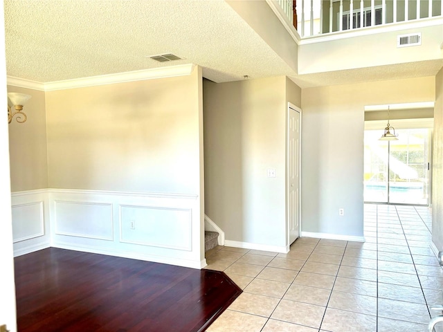 tiled spare room with ornamental molding and a textured ceiling