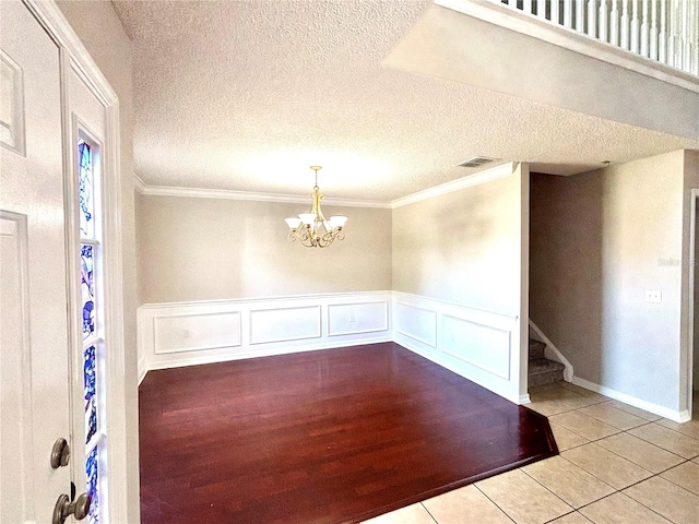 unfurnished room featuring a notable chandelier, a textured ceiling, and light hardwood / wood-style floors