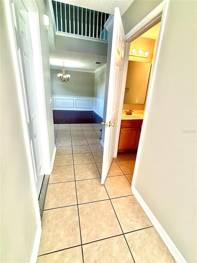 hall featuring sink, a textured ceiling, light tile patterned floors, and an inviting chandelier