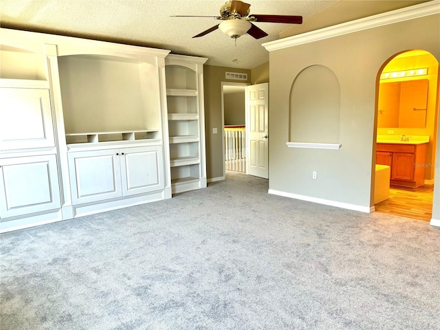 unfurnished living room with ornamental molding, sink, light colored carpet, a textured ceiling, and ceiling fan