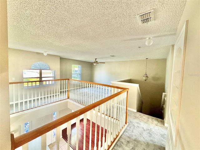 hall featuring a textured ceiling and carpet flooring