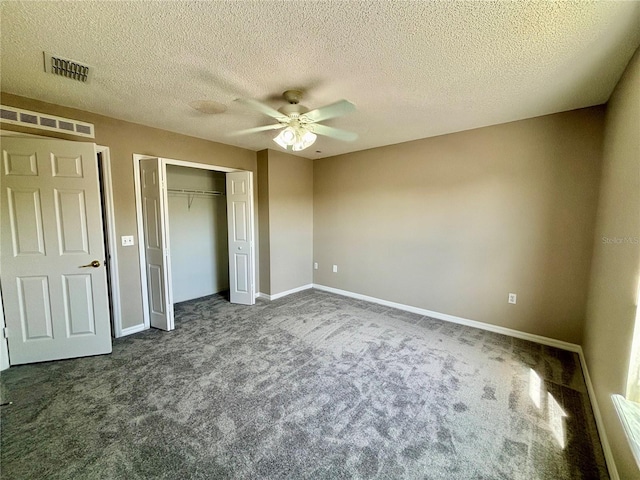 unfurnished bedroom featuring dark colored carpet, a closet, a textured ceiling, and ceiling fan