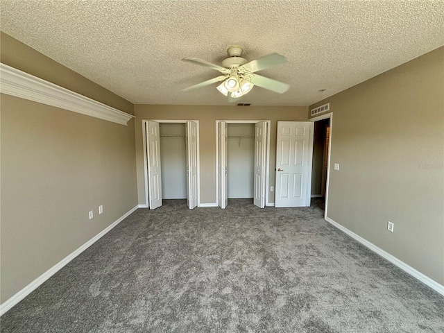 unfurnished bedroom featuring multiple closets, carpet, a textured ceiling, and ceiling fan