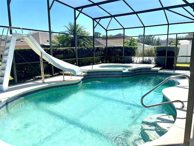 view of pool with an in ground hot tub, a water slide, and a lanai