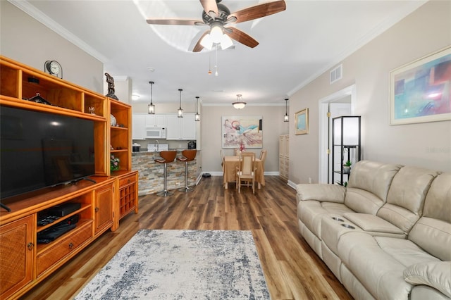 living room with ceiling fan, ornamental molding, and dark hardwood / wood-style floors