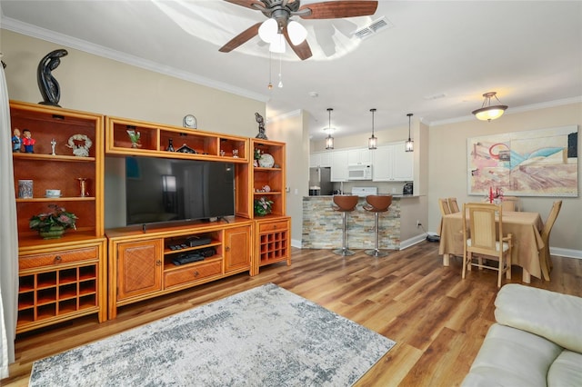 living room with crown molding, light wood-type flooring, and ceiling fan