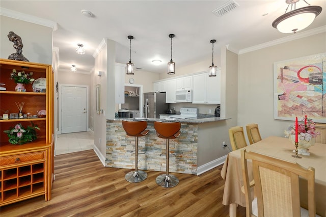 kitchen with kitchen peninsula, white cabinetry, wood-type flooring, and white appliances