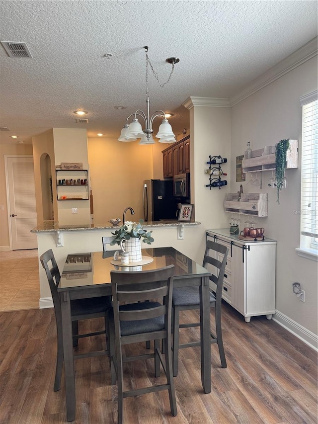 dining space with a notable chandelier, hardwood / wood-style flooring, a wealth of natural light, and a textured ceiling