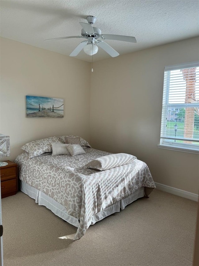 bedroom with ceiling fan, a textured ceiling, and carpet flooring