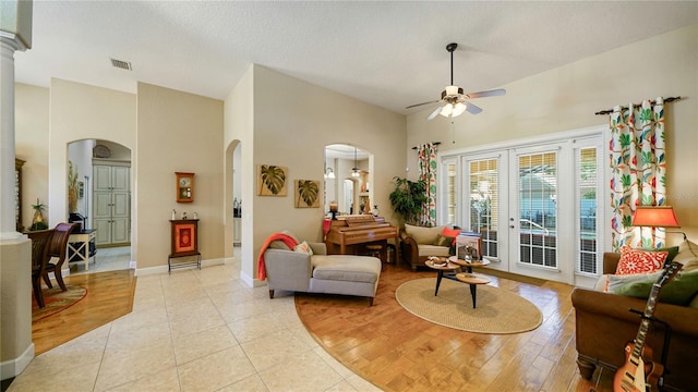 living room with ceiling fan, a textured ceiling, ornate columns, a high ceiling, and light hardwood / wood-style floors