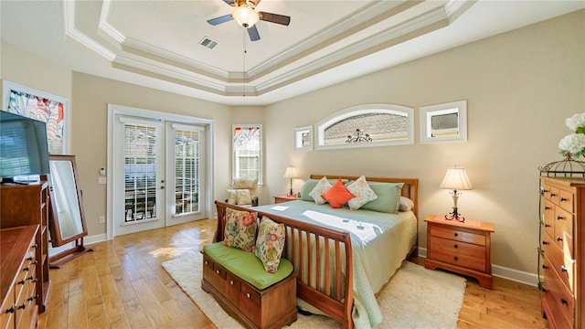 bedroom featuring access to outside, a tray ceiling, light hardwood / wood-style floors, ceiling fan, and crown molding