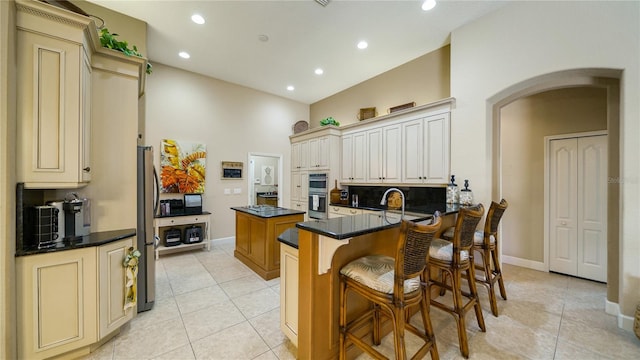 kitchen with decorative backsplash, a kitchen island, kitchen peninsula, a breakfast bar, and light tile patterned flooring