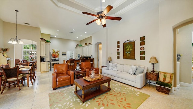 tiled living room featuring a towering ceiling, crown molding, and ceiling fan with notable chandelier